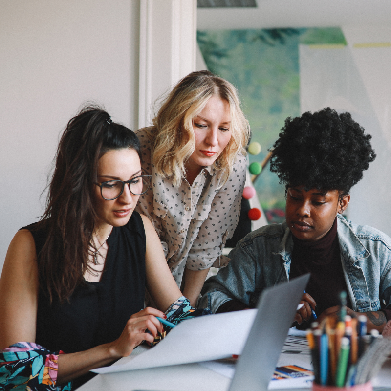 Three women looking over paperwork at a desk